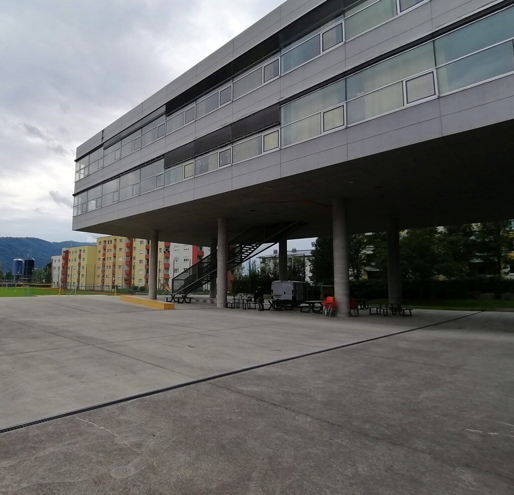 Im Bild ist ein leerer vollversiegelter Beton-Innenhof eines Schulgebäudes zu sehen.