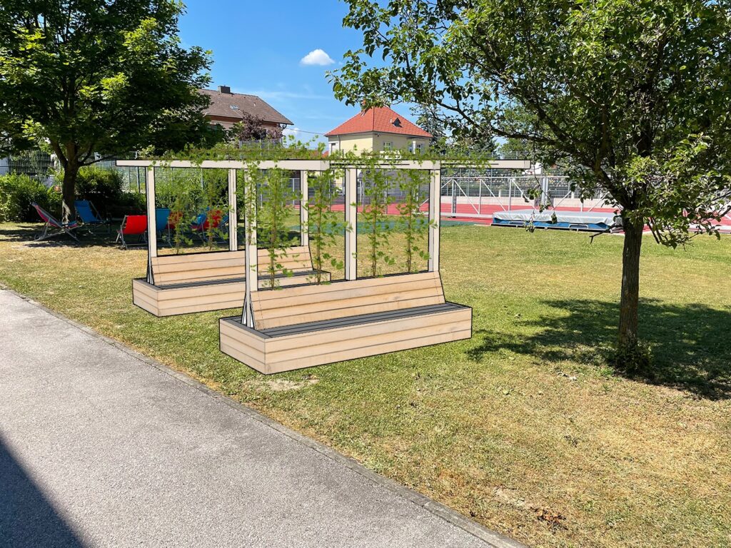 Im Bild ist eine Fotomontage zu sehen, die eine begrünte Pergola-Sitzkonstruktion auf einer Schulwiese zeigt.