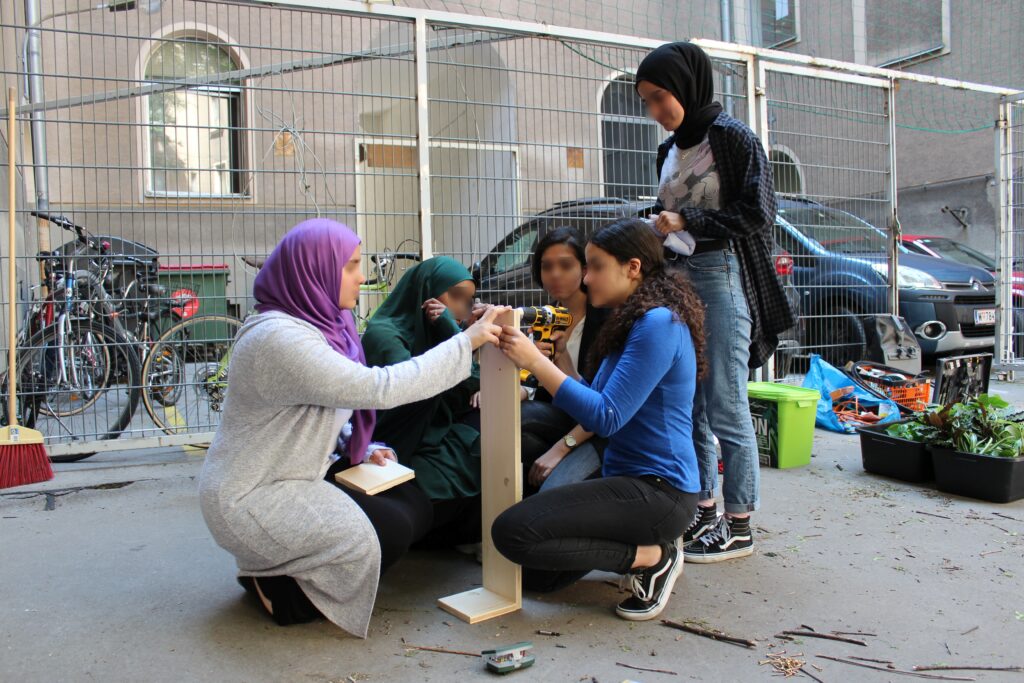 Im Bild sind Schüler*innen zu sehen, die Holzplatten zusammenschrauben.