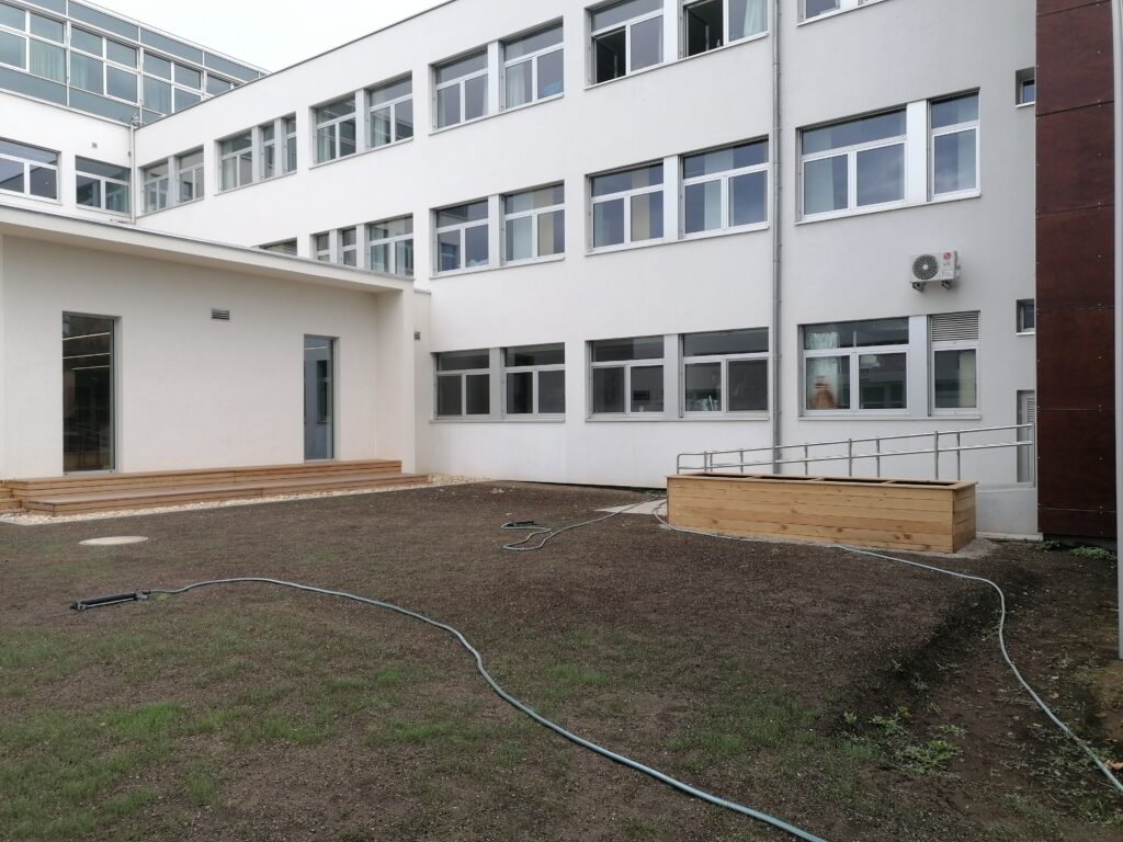 Im Bild ist ein frisch sanierter Schulhof mit Hochbeet zu sehen.